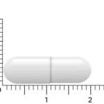 Neben einem Lineal ist eine weiße Vitakruid - Zink-Methionin & Kupfer Kapsel (90 vegane Kapseln) mit einer Länge von etwa 2 Zentimetern abgebildet.