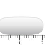 Eine weiße, längliche Vitakruid-GABA-Plus-Pille (90 Schmelztabletten) wird neben ein Lineal gelegt, sodass ersichtlich ist, dass sie ungefähr 2 Zentimeter lang ist.